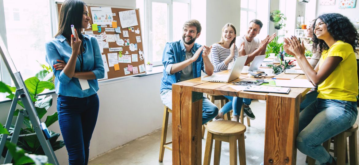Group of business colleagues at startup, clapping for employee who was promoted from within the organization.